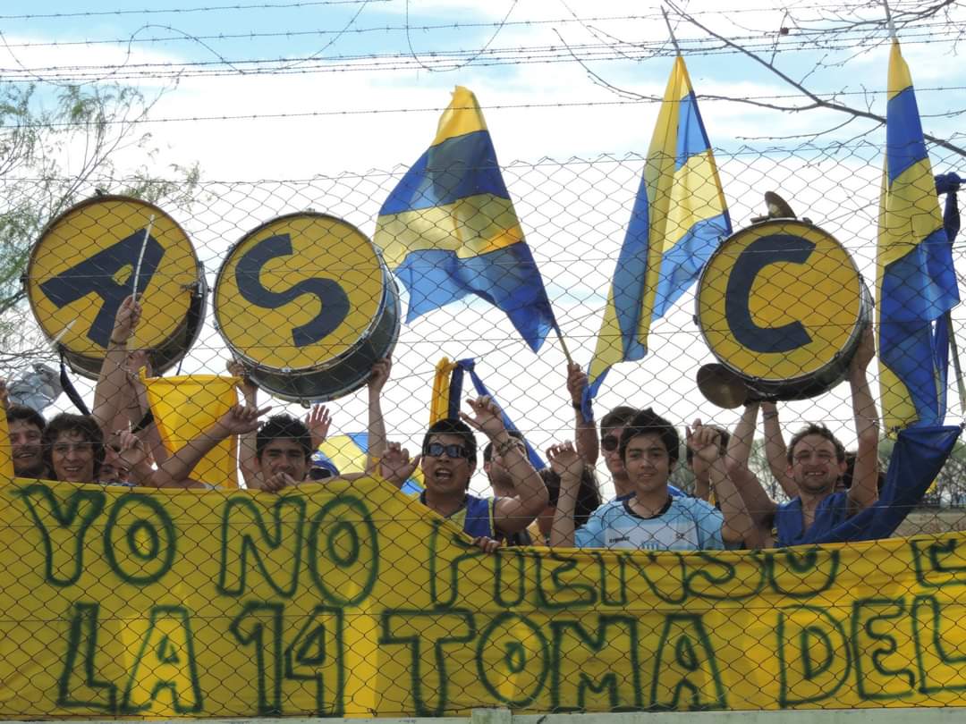 Hinchada de ANCALU con bombos ASC, banderas azules y amarillas y humo